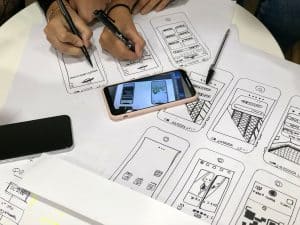Zwei Personen befinden sich im UX Design Prozess und zeichnen Bilder von einem Handy ab.
