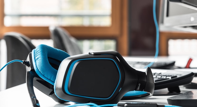 Schwarz-blaue Kopfhörer liegen zum Online-Lernen auf einem Schreibtisch.