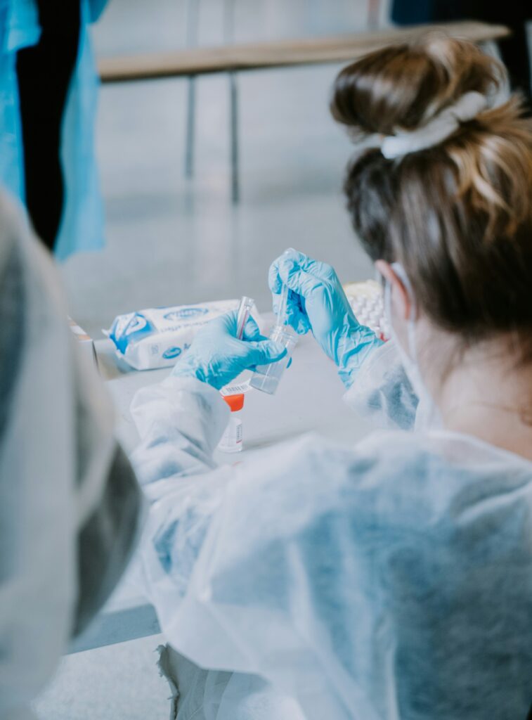 Eine Frau trägt blaue Handschuhe und geht ihrer Arbeit im Labor nach.