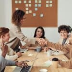 Kolleg:innen in einem Meeting schütteln sich die Hand
