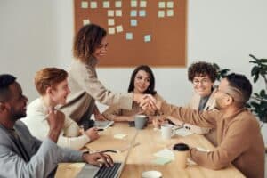 Kolleg:innen in einem Meeting schütteln sich die Hand